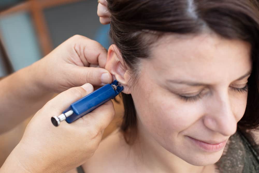 Woman having ear piercing process